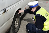 Policjant z drogówki kontroluje stan ogumienia samochodu dostawczego