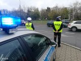zdjęcie - radiowóz ustawiony prostopadle do drogi, przed nim policjantka i policjant z drogówki - zdjęcie poglądowe z archiwum policja.pl