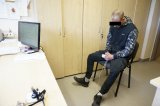 zdjęcie - sprawca w trakcie przesłuchania - mężczyzna w kajdankach na rękach i nogach siedzi na krześle w pomieszczeniu biurowym