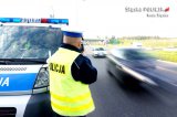 zdjęcie - policjant przy radiowozie dokonujący pomiaru prędkości przejeżdżających pojazdów