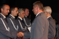 Zdjęcie z uroczystości Święta Policji przedstawia wręczanie aktów nominacyjnych ustawionym w rzędzie funkcjonariuszom