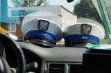 zdjęcie przedstawia wnętrze radiowozu i dwie czapki policjantów z drogówki