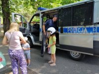zdjęcie przedstawia spotkanie w ramach Ogrodów śniadaniowych - na zdjęciu radiowóz policyjny i dzieci z mamą przed nim