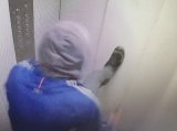 zdjęcie przedstawia wizerunek sprawcy zniszczenia drzwi windy, ubrany w niebieską bluzę, szary kaptur