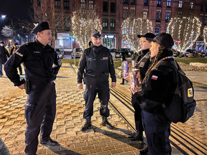 zdjęcie przedstawia policjantów rozmawiających z kwestującymi młodymi uczennicami klasy policyjnej
