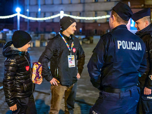 zdjęcie przedstawia policjantów rozmawiających z kwestującym mężczyzną i chłopcem z puszką