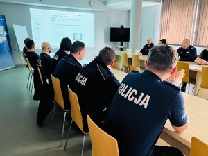 zdjęcie przedstawia salę narad komendy w czasie szkolenia, policjanci siedzą przy stołach, uczestnicząc w dyskusji