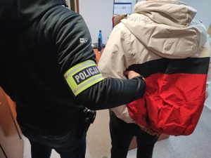 zdjęcie przedstawia policjanta po cywilu z zatrzymanym 18-latkiem